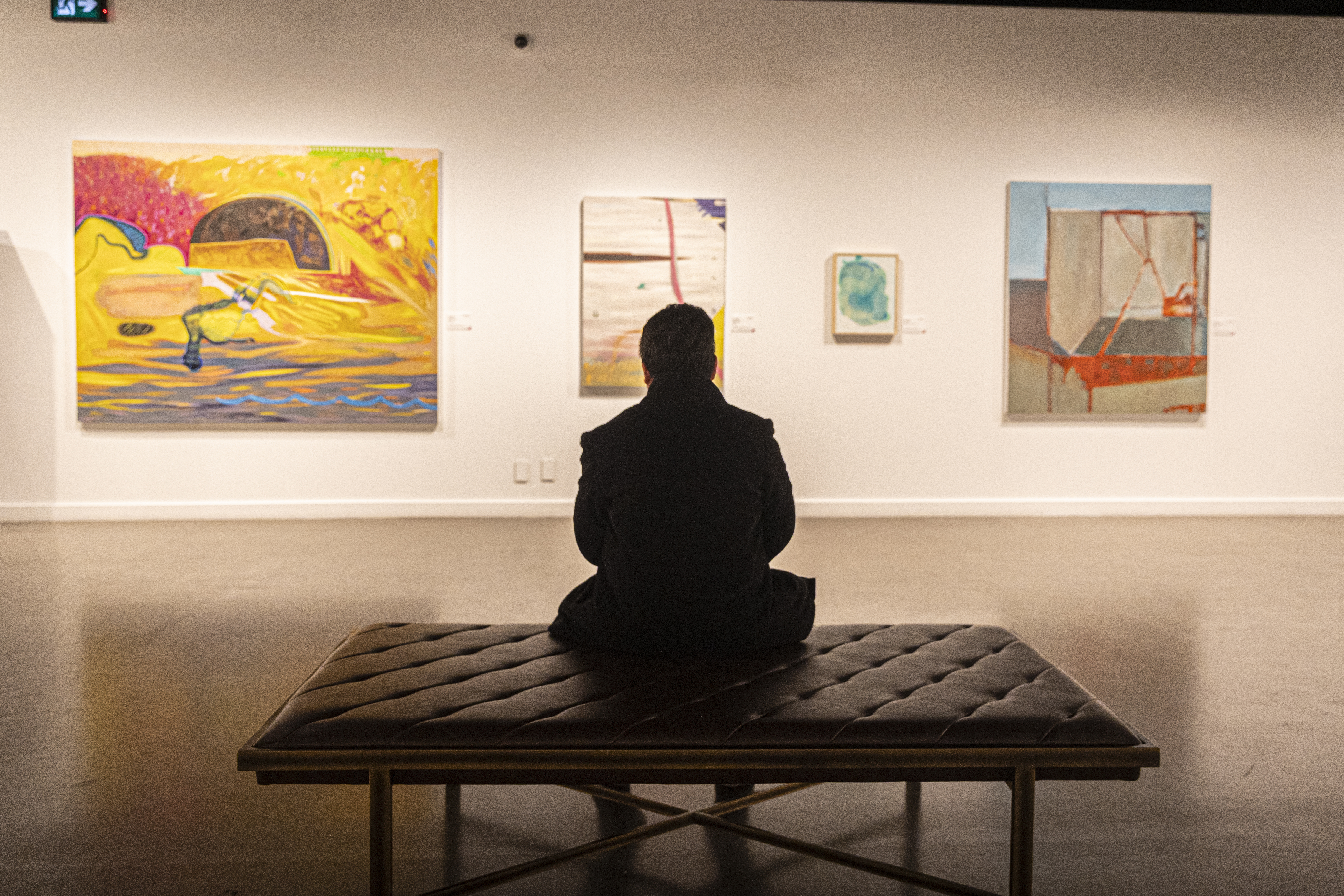 An attendee is sitting down while taking in the artworks on display at the AFA art house.