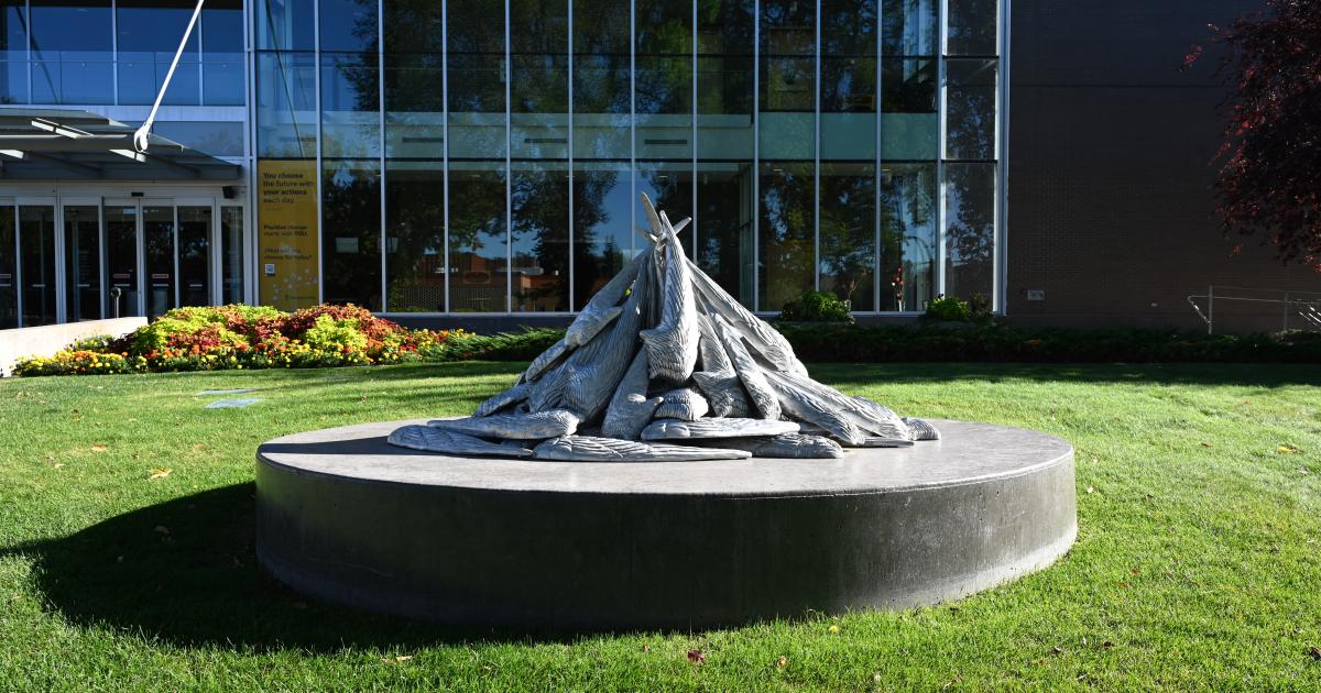 A photo of Blake Senini’s public artwork Turn Turn Turn, which depicts the wings of an arctic tern enlarged to human scale. It is placed in a greenspace in front of a public building. 