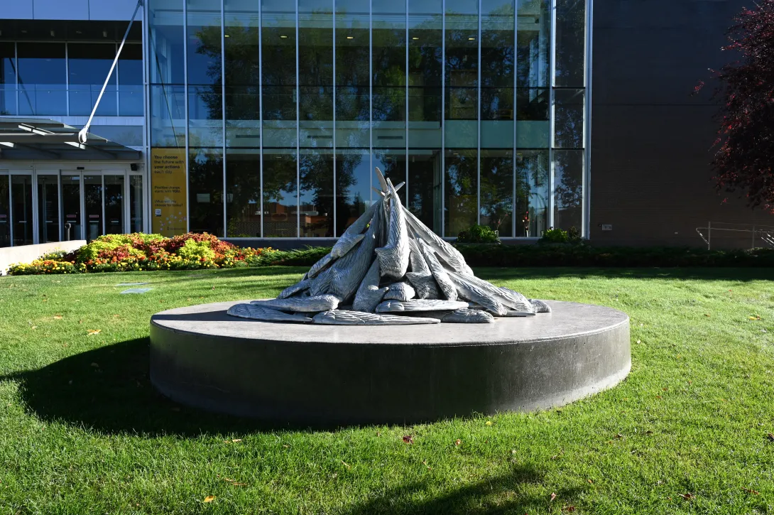 A photo of Blake Senini’s public artwork Turn Turn Turn, which depicts the wings of an arctic tern enlarged to human scale. It is placed in a greenspace in front of a public building. 